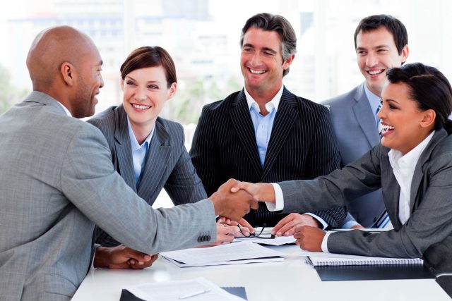 a group of business people shaking hands at a table.